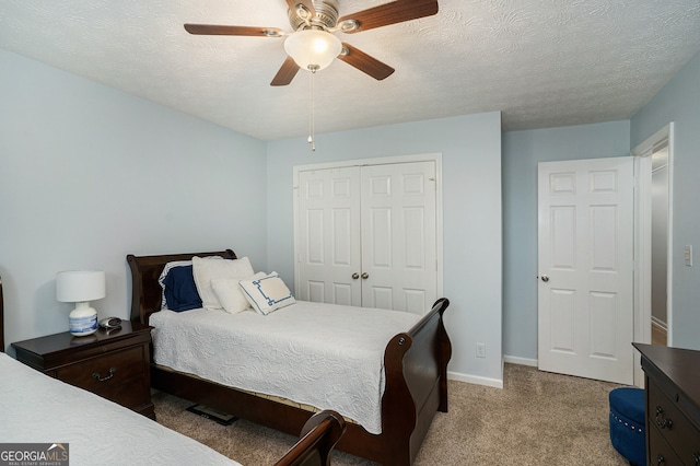 bedroom featuring a textured ceiling, a closet, ceiling fan, and light colored carpet