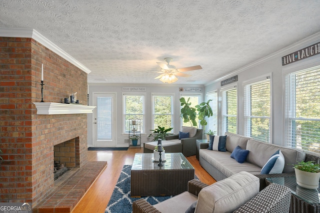 living room with a textured ceiling, a fireplace, wood-type flooring, and crown molding