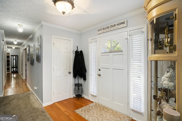 foyer featuring wood-type flooring, a textured ceiling, and ornamental molding