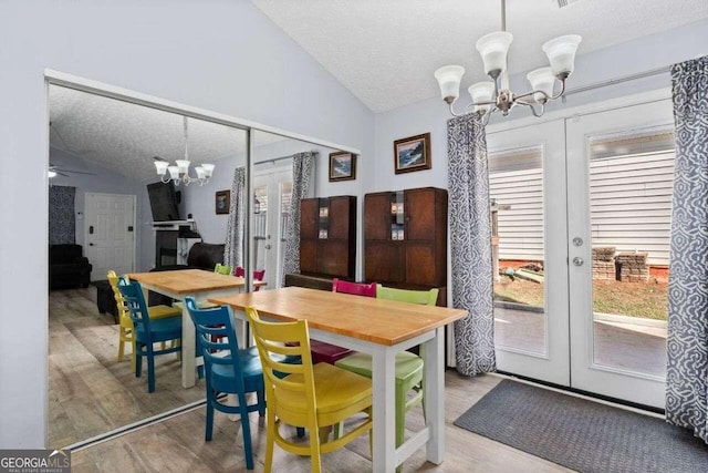 dining room featuring french doors, ceiling fan with notable chandelier, a textured ceiling, wood-type flooring, and lofted ceiling