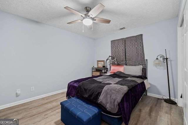 bedroom featuring ceiling fan, light hardwood / wood-style floors, and a textured ceiling