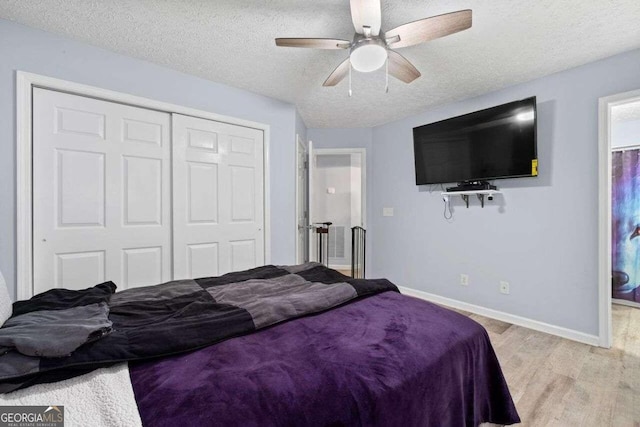 bedroom with a textured ceiling, a closet, light hardwood / wood-style flooring, and ceiling fan