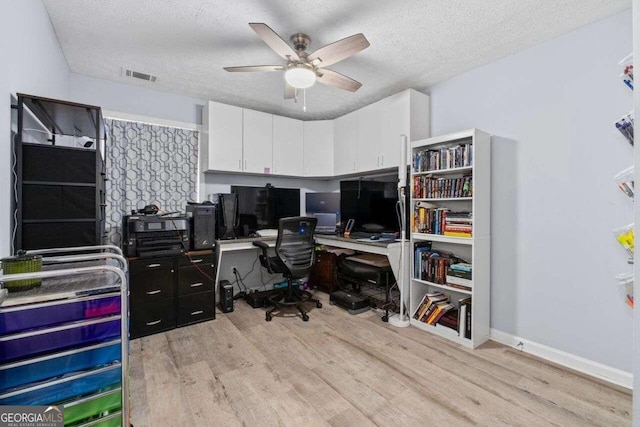 home office with a textured ceiling, light hardwood / wood-style floors, and ceiling fan