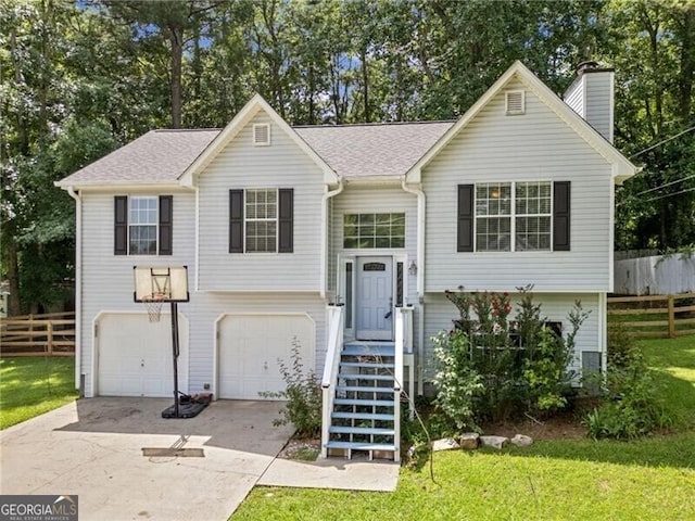 raised ranch featuring a garage and a front lawn