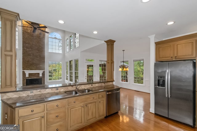 kitchen featuring light wood-type flooring, decorative columns, stainless steel appliances, sink, and pendant lighting