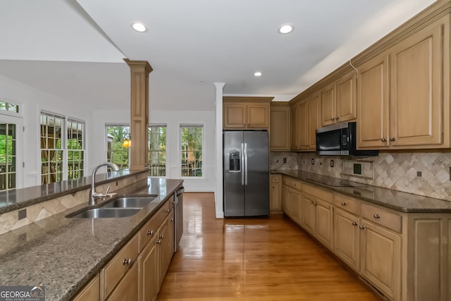 kitchen featuring sink, decorative backsplash, ornate columns, appliances with stainless steel finishes, and light hardwood / wood-style floors