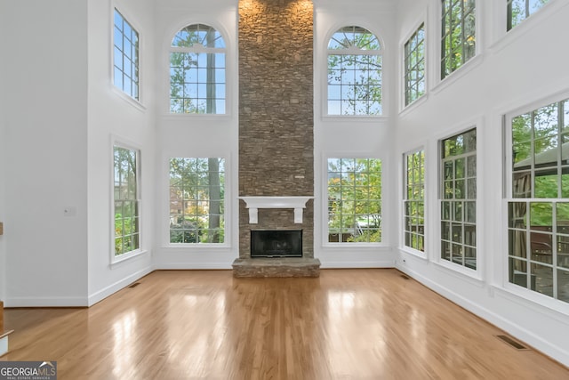 unfurnished living room featuring plenty of natural light, a high ceiling, and light hardwood / wood-style flooring