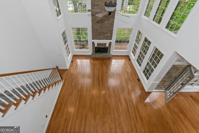 unfurnished living room featuring a wealth of natural light, hardwood / wood-style floors, ceiling fan, and a high ceiling