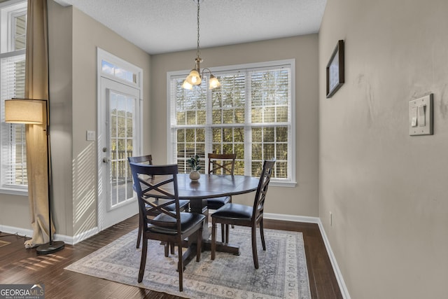 dining space featuring dark hardwood / wood-style floors, a textured ceiling, and an inviting chandelier