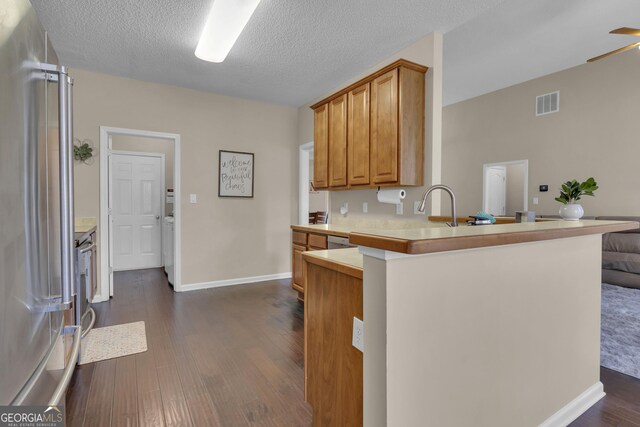 kitchen with dark wood-type flooring, high end refrigerator, ceiling fan, a textured ceiling, and kitchen peninsula