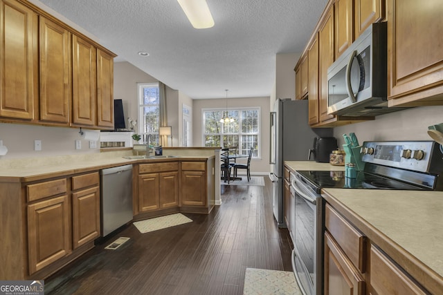 kitchen with sink, hanging light fixtures, dark hardwood / wood-style floors, appliances with stainless steel finishes, and a notable chandelier