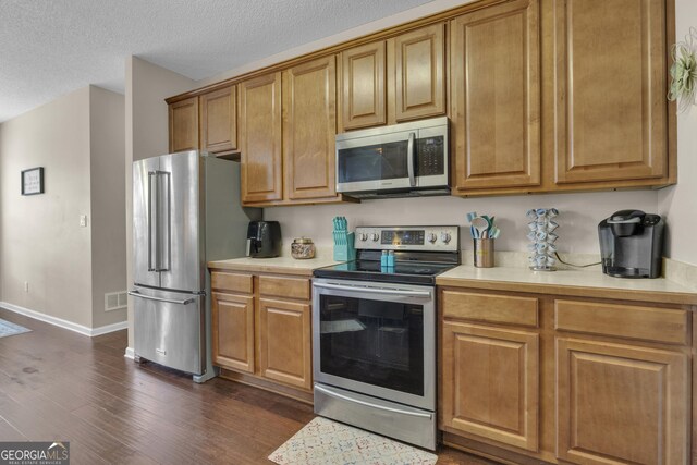 kitchen featuring a textured ceiling, dark wood-type flooring, and appliances with stainless steel finishes