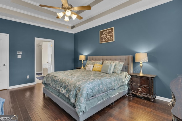 bedroom featuring ceiling fan, a raised ceiling, dark hardwood / wood-style flooring, ensuite bathroom, and ornamental molding