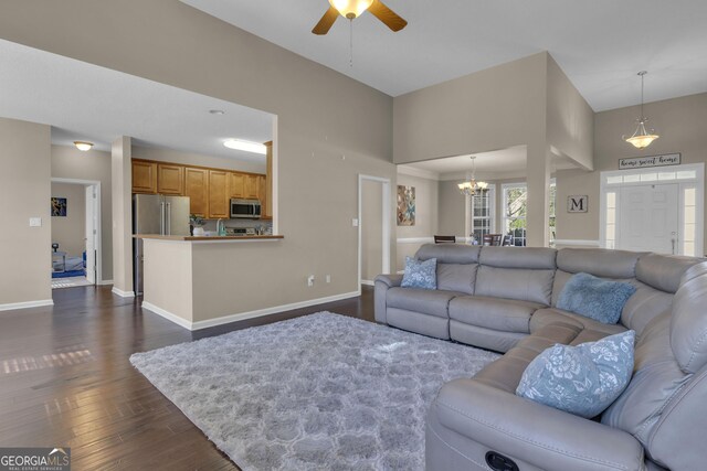 living room with dark wood-type flooring and ceiling fan with notable chandelier