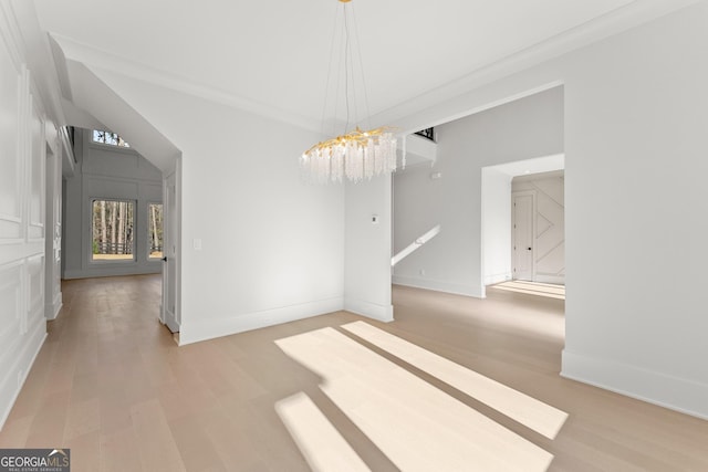 unfurnished room featuring ornamental molding, a chandelier, and light hardwood / wood-style floors