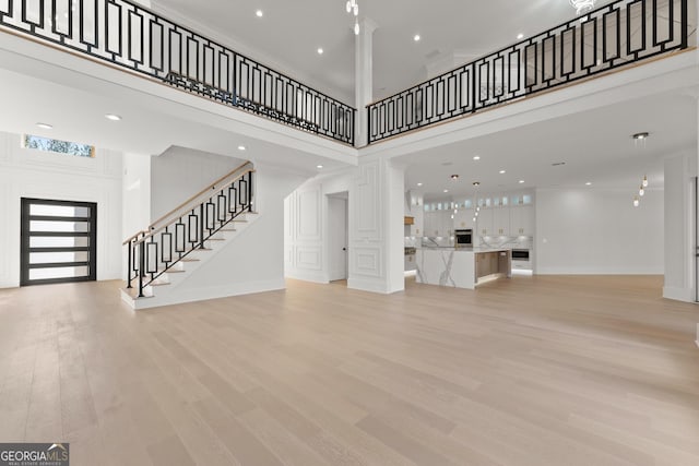 unfurnished living room featuring a towering ceiling and light wood-type flooring