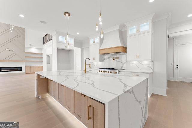 kitchen featuring white cabinets, premium range hood, and a spacious island