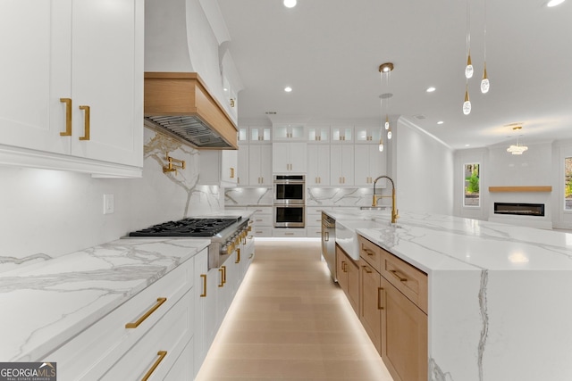 kitchen featuring sink, hanging light fixtures, appliances with stainless steel finishes, light stone counters, and white cabinetry