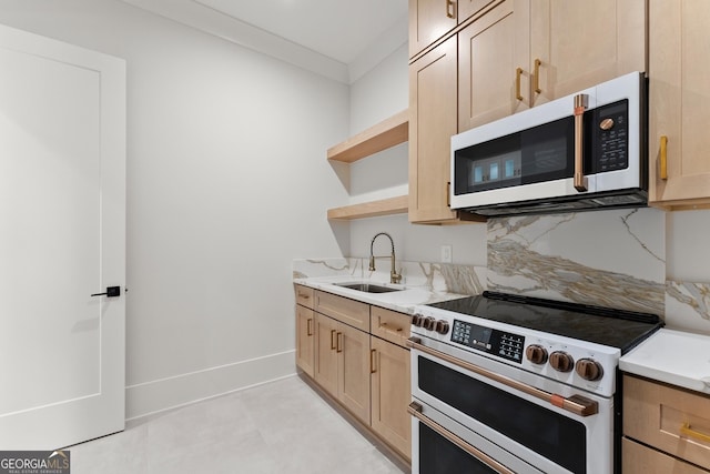 kitchen with appliances with stainless steel finishes, light stone counters, light brown cabinetry, and sink