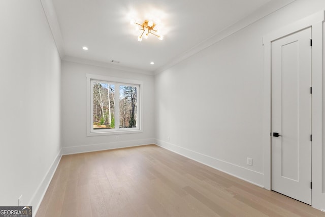 empty room featuring light wood-type flooring and crown molding