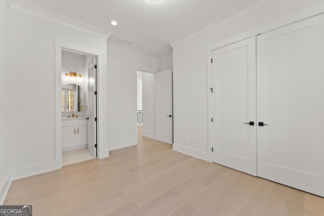 unfurnished bedroom featuring connected bathroom, light hardwood / wood-style flooring, a closet, and ornamental molding