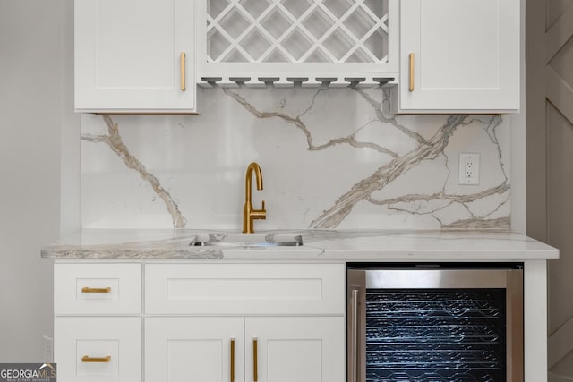 bar with white cabinets, backsplash, sink, and beverage cooler