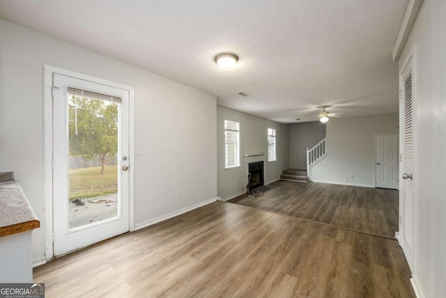 unfurnished living room with ceiling fan, a textured ceiling, and hardwood / wood-style flooring