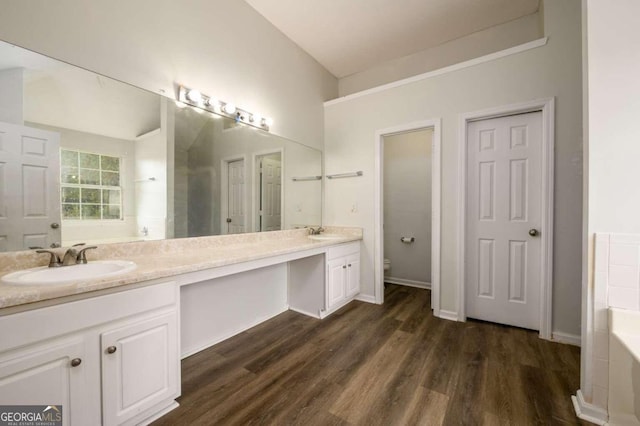 bathroom featuring wood-type flooring, vanity, toilet, and a bathtub