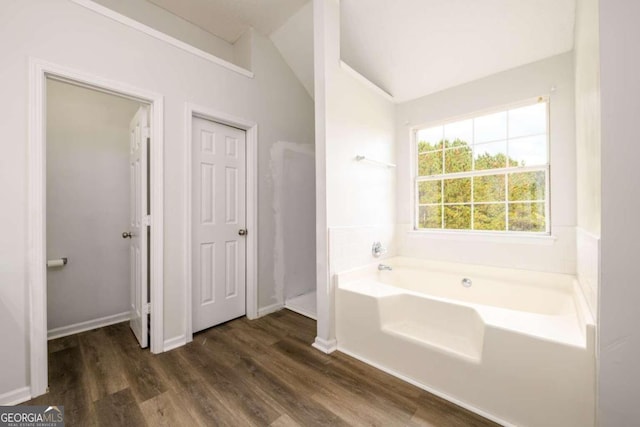 bathroom featuring a tub, wood-type flooring, and vaulted ceiling