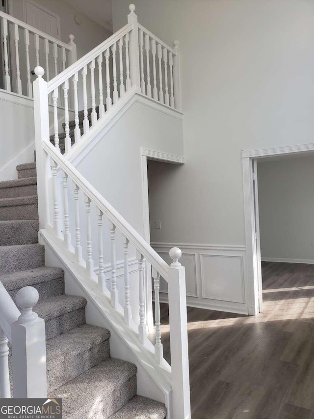 stairs with a towering ceiling and hardwood / wood-style flooring