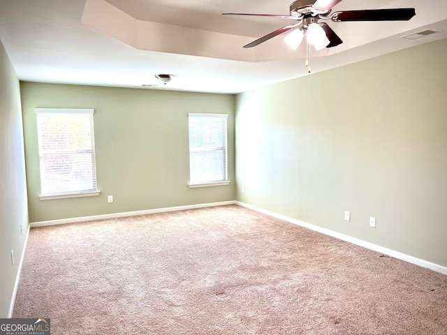 carpeted spare room featuring ceiling fan and plenty of natural light