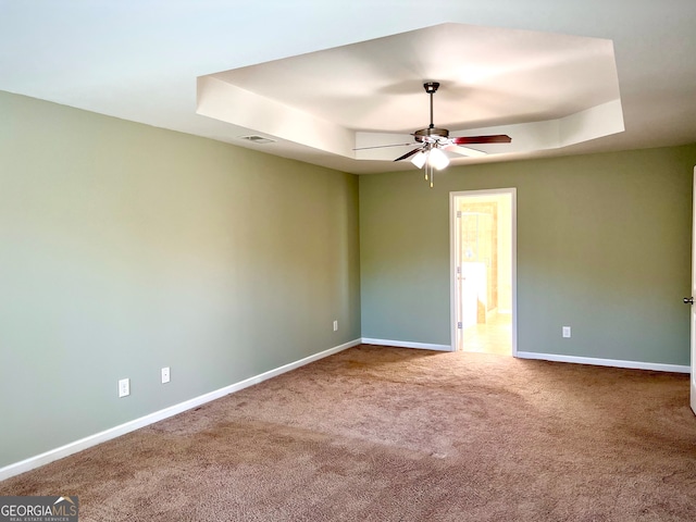 unfurnished room featuring carpet, ceiling fan, and a raised ceiling