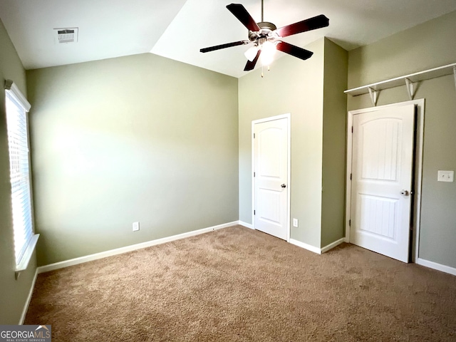 unfurnished bedroom featuring carpet flooring, a closet, vaulted ceiling, and ceiling fan