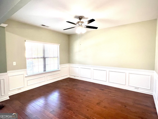 unfurnished room with ornate columns, ceiling fan, and dark wood-type flooring