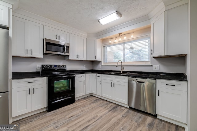 kitchen featuring white cabinets, appliances with stainless steel finishes, light hardwood / wood-style flooring, and sink