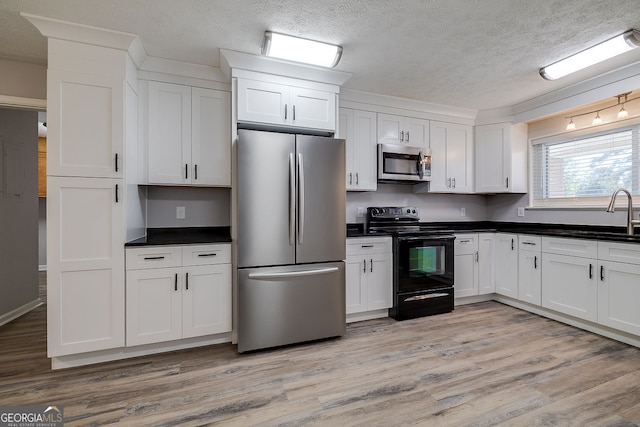 kitchen featuring white cabinetry, sink, light wood-type flooring, and stainless steel appliances