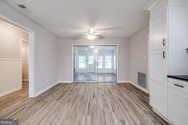 unfurnished living room featuring ceiling fan, light hardwood / wood-style floors, and a textured ceiling