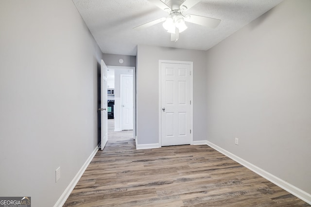 interior space with ceiling fan, wood-type flooring, and a textured ceiling