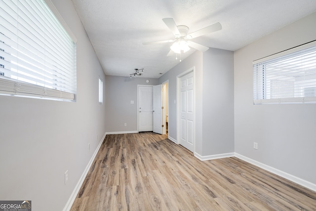 empty room with ceiling fan, light hardwood / wood-style floors, and a textured ceiling