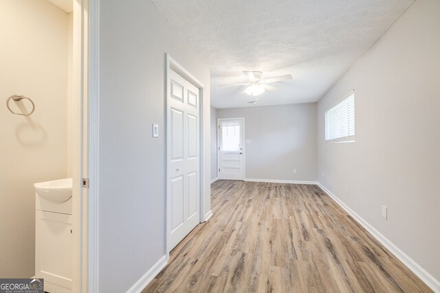 interior space with ensuite bath, ceiling fan, light hardwood / wood-style flooring, and a textured ceiling