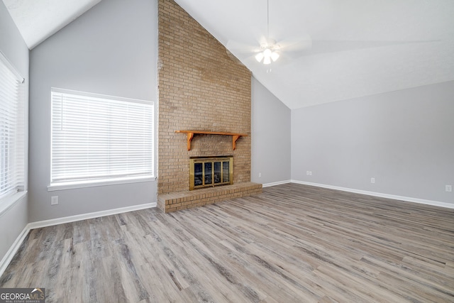 unfurnished living room featuring ceiling fan, a fireplace, high vaulted ceiling, and light hardwood / wood-style floors