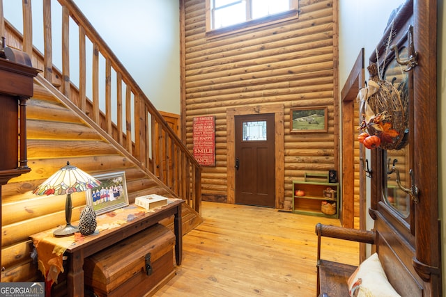 foyer entrance with rustic walls, a healthy amount of sunlight, and light hardwood / wood-style floors