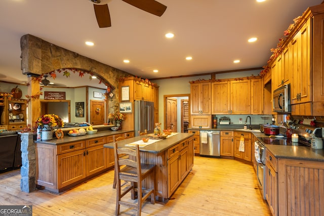 kitchen featuring ornamental molding, a center island, stainless steel appliances, and light hardwood / wood-style flooring