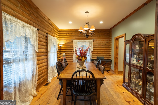 dining area with log walls, light wood-type flooring, and a notable chandelier