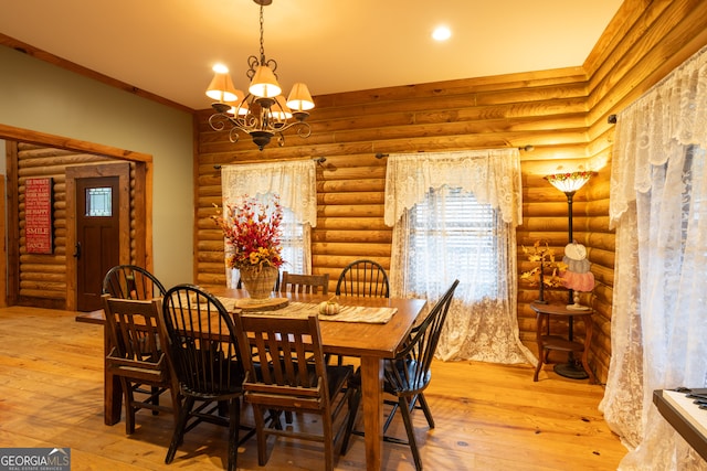 dining space with an inviting chandelier, light hardwood / wood-style flooring, rustic walls, and ornamental molding