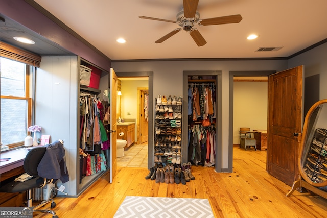 bedroom featuring light hardwood / wood-style flooring, ensuite bath, crown molding, and ceiling fan