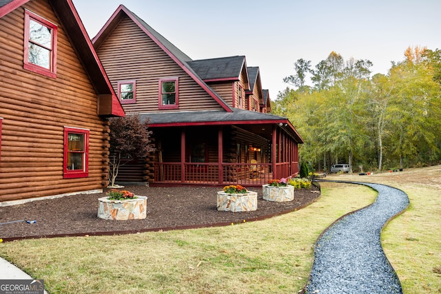 rear view of house with a porch and a yard