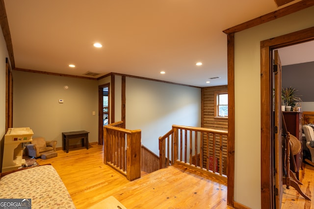 corridor with light hardwood / wood-style floors and crown molding