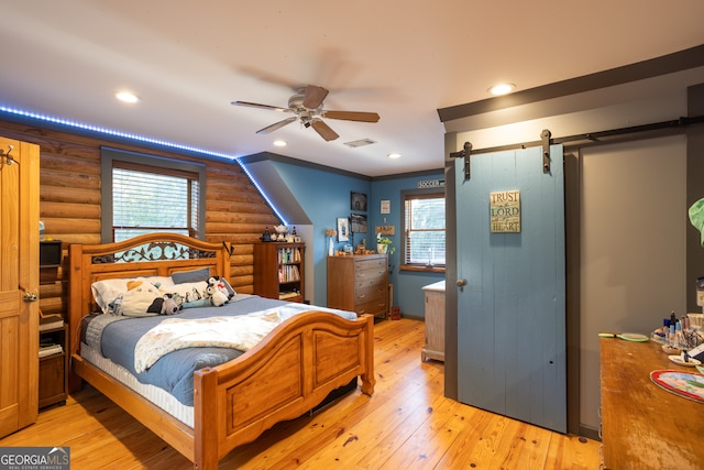 bedroom featuring rustic walls, multiple windows, and light wood-type flooring