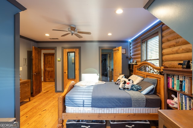 bedroom with ceiling fan, log walls, ornamental molding, and light wood-type flooring